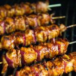 Vertical photo of Barbecued Chicken Skewers cooking on a grill.