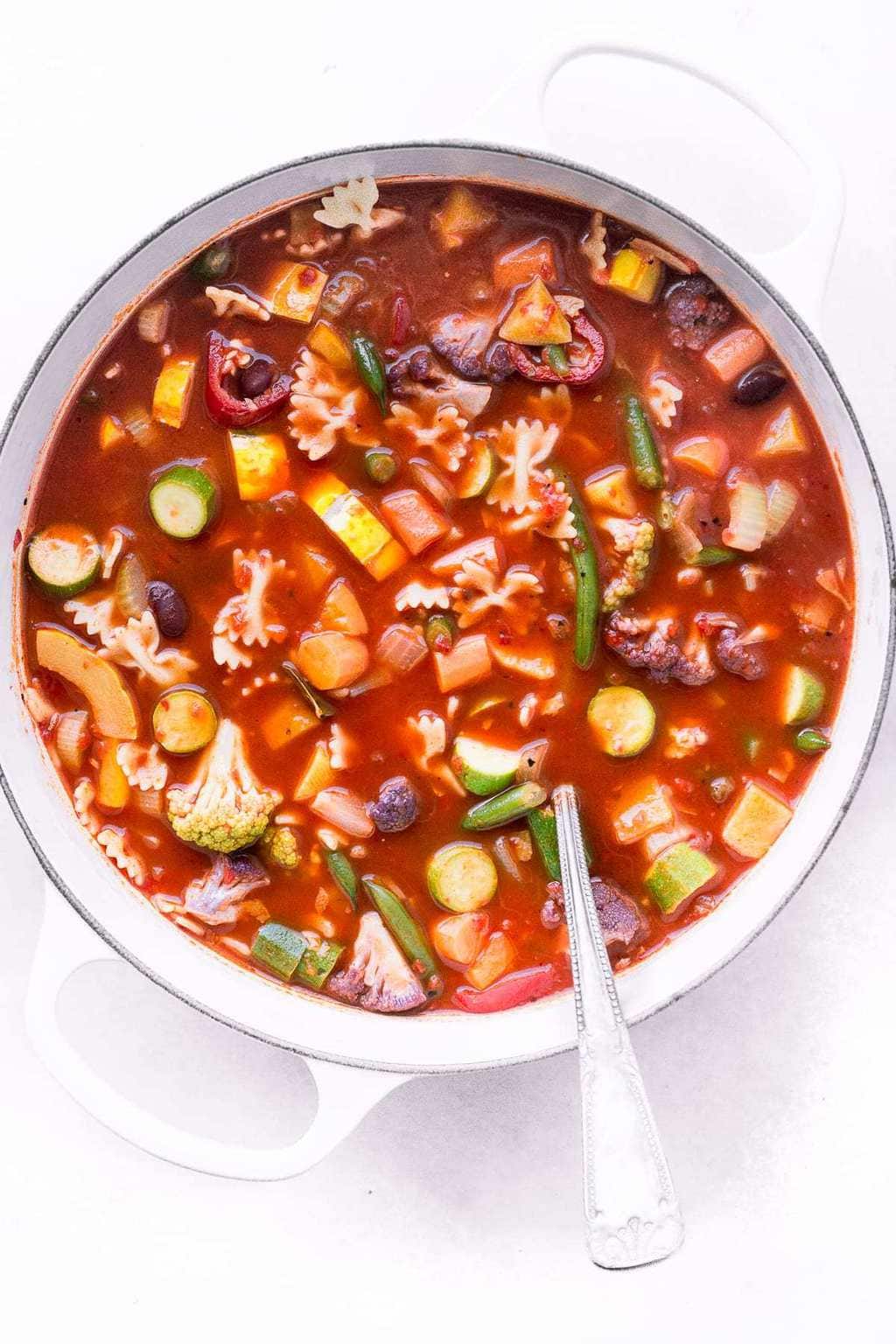 Overhead pictures of a big pot of Minestrone soup on a white background