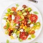Vertical overhead photo of an Essence of Summer Caprese Salad on a white serving plate with graphics at the bottom of the photo.